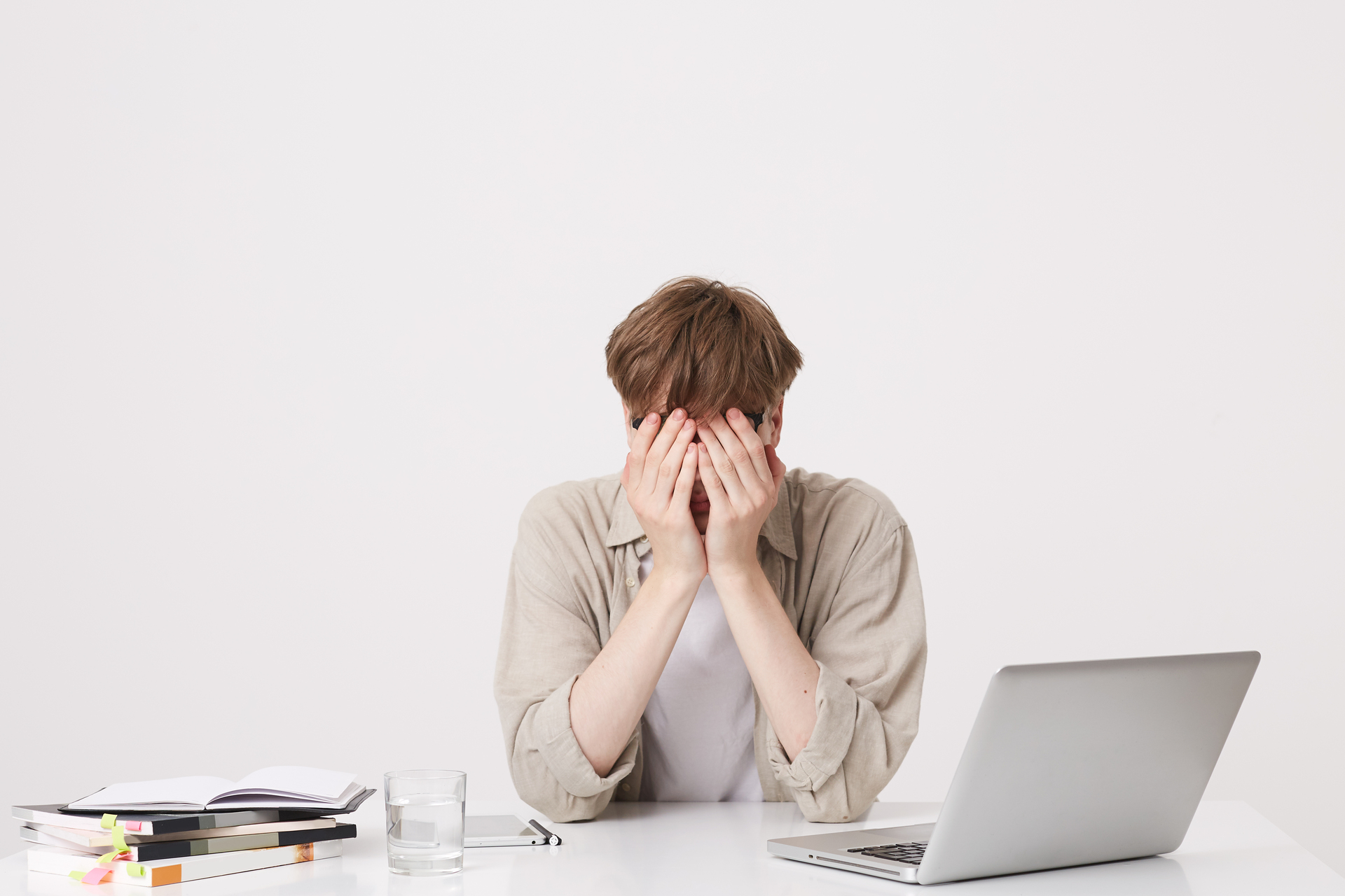 closeup-cheerful-young-male-student-with-braces-wears-beige-shirt-study-using-laptop-computer-notebooks-sitting-table-isolated-white-wall (1)